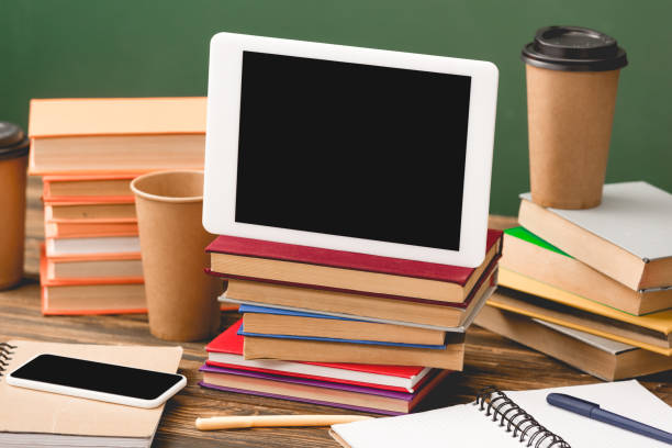 istock books, notebooks, pens, disposable cups, smartphone and digital tablet with blank screen on wooden surface isolated on green 1152821192