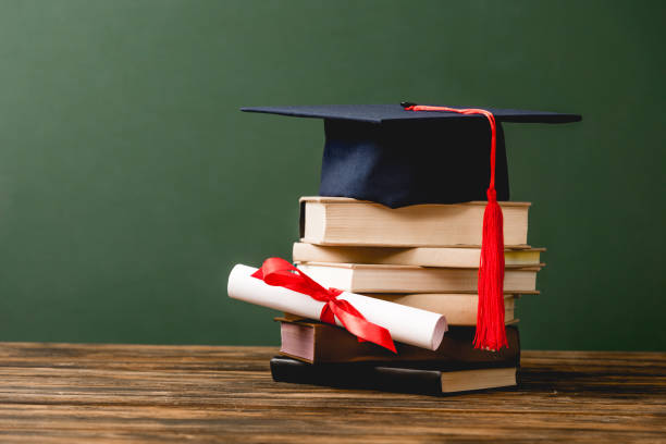 istock books, academic cap and diploma on wooden surface isolated on green 1152821203