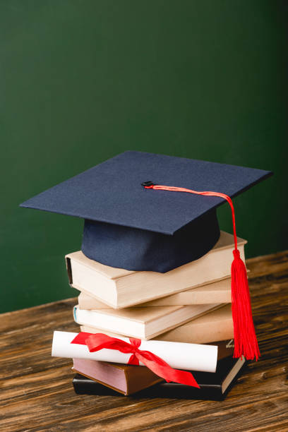 istock books, academic cap and diploma on wooden surface on green 1152821213