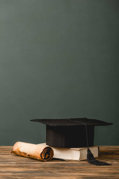 istock book, academic cap and scroll on wooden surface isolated on grey 1152821261