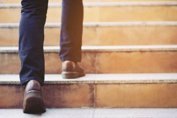 hombre de negocios moderno que trabaja cerca de las piernas caminando por las escaleras en la ciudad moderna. en hora punta para trabajar en la oficina una prisa. durante la primera mañana de trabajo. escalera. enfoque suave. - vertical ramp fotografías e imágenes de stock