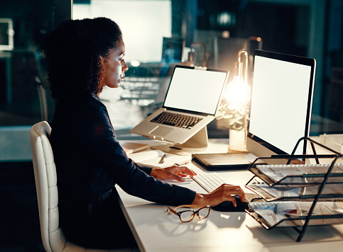 Shot of a young businesswoman working on a computer in an office at night