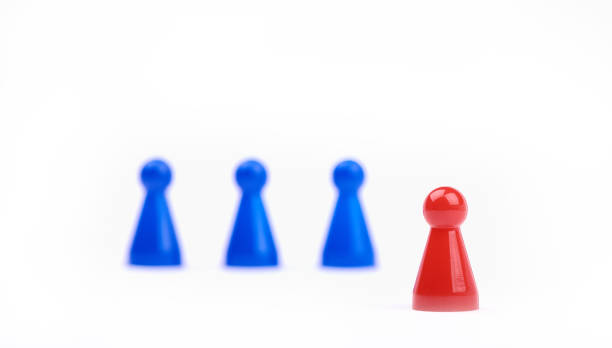 istock Three blurred blue game pieces as a team and one red sharpened figure as a leader in the foreground. Closeup photo with selective focus isolated on white background 1152823761