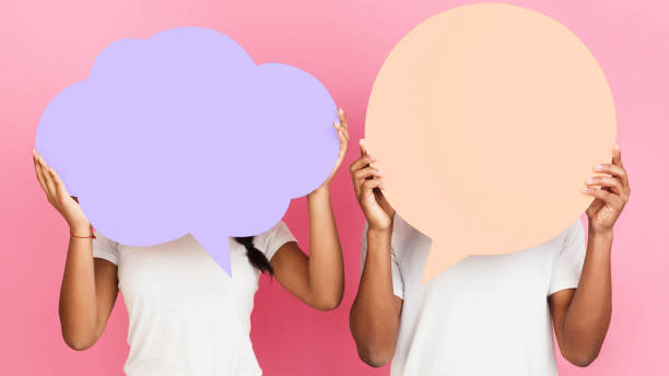istock Couple holding blank speech bubbles, pink background 1152823901