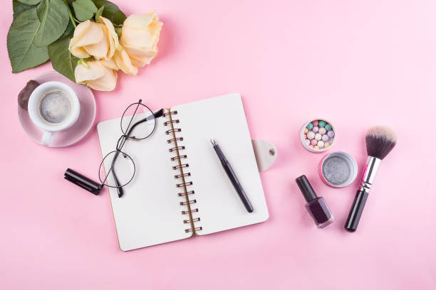 istock Workplace mockup with notebook, glasses, roses and accessories on pink background top view. Flat lay with coffee copy space. Feminine working style concept. 1152823970