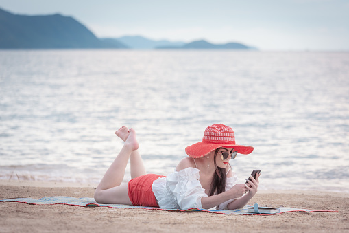 Beautiful woman at the beach relaxing watching the sunset