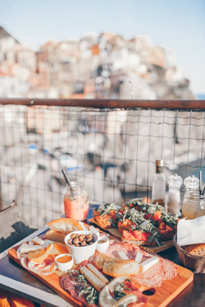 gustoso spuntino italiano. bruschette fresche, formaggi e carne sulla tavola in un caffè all'aperto con vista mozzafiato a manarola - manarola foto e immagini stock