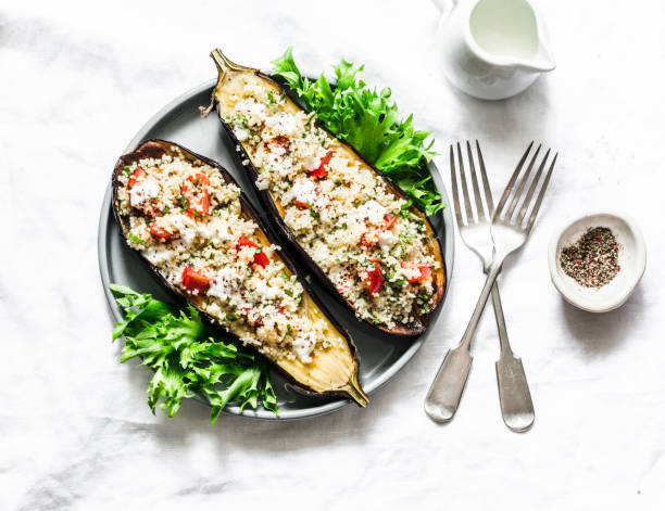 istock Baked eggplant stuffed with couscous, tomatoes, cilantro with yogurt sauce on a light background, top view 1152827593