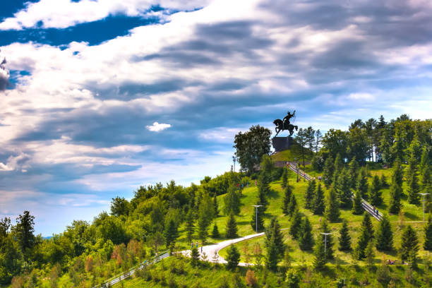 The main monument of Bashkiria on a green summer hill in the park with walkways and stairs under beautiful dramatic blue clouds in the sky.