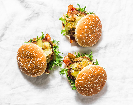 Classic homemade burger with pork cutlet, bacon, pickles, fried onions and mayonnaise mustard sauce on light background. Copy space