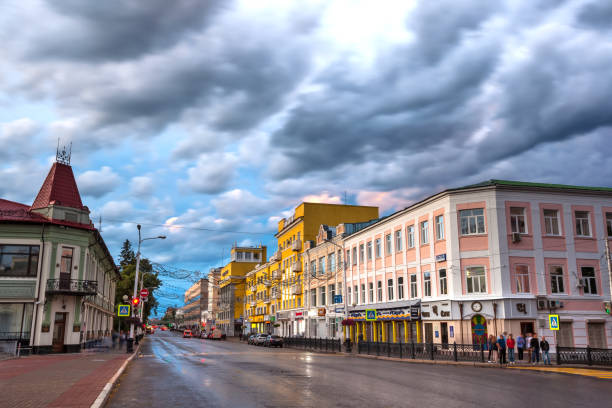 The city center with low modern houses, people stand on a pedestrian crossing after the rain under dark thick clouds.
