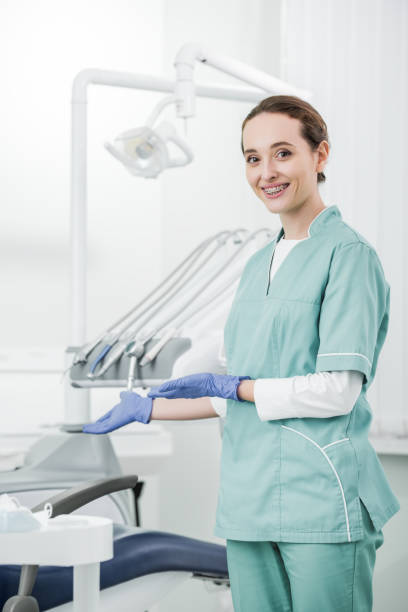 istock attractive dentist with braces on teeth smiling while gesturing in dental clinic 1152830270