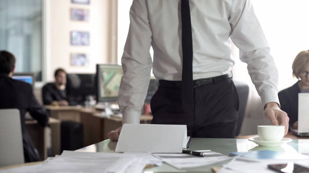 istock Male boss looking through documentation and drinking tea, standing in his office 1152830382