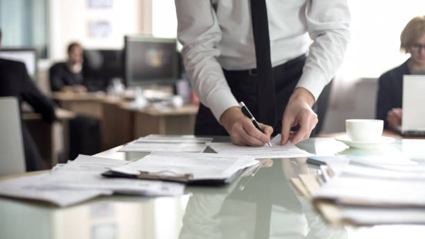 istock Head of department signing documents, employees working on background, office 1152830384
