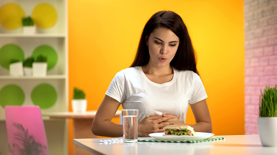 Mujer tocando el estómago después de comida alta en calorías, problema de comer en exceso, gastritis photo