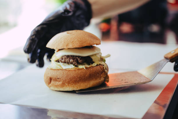 istock Cook preparing burger adding the sauce on the cream cheese. Three burgers. 1152830769