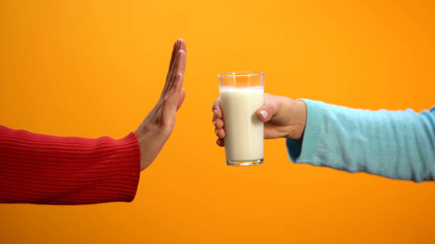 Female refusing to drink milk showing stop gesture on bright background, health stock photo