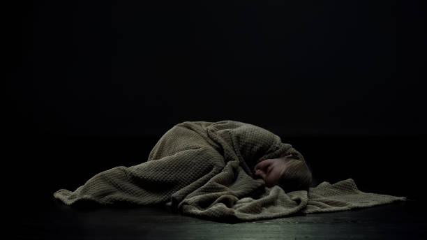 Girl covered in plaid lying on floor of dark room, domestic violence victim Girl covered in plaid lying on floor of dark room, domestic violence victim dictator photos stock pictures, royalty-free photos & images