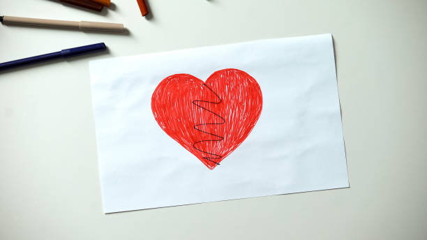 istock Broken heart drawing lying on table, divorce and family problems concept 1152830895