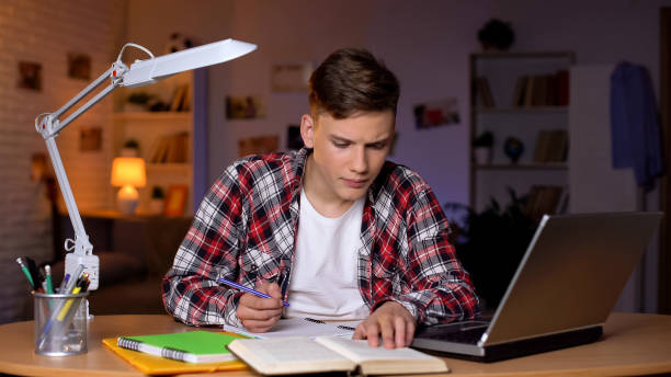 istock Student reading task in book and writing answer down to copybook, homework 1152831158