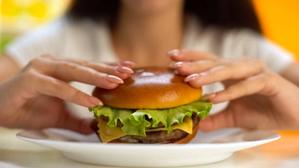istock Female hands taking tasty cheeseburger from white plate closeup, cholesterol 1152831162