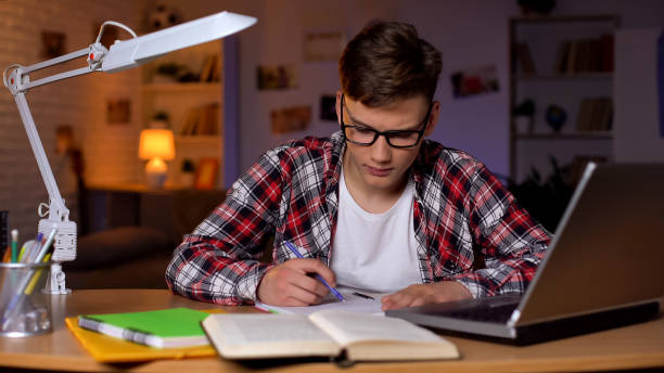 istock Concentrated student in glasses doing his hometask, working on school project 1152831209