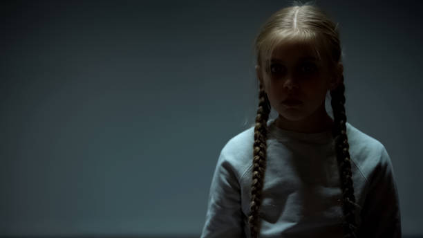 istock Unhappy kid looking at camera, standing alone in dark room, violence victim 1152831307