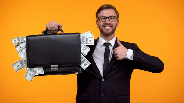 istock Man showing case packed with money, doing thumbs-up, loan, easy crediting 1152831340