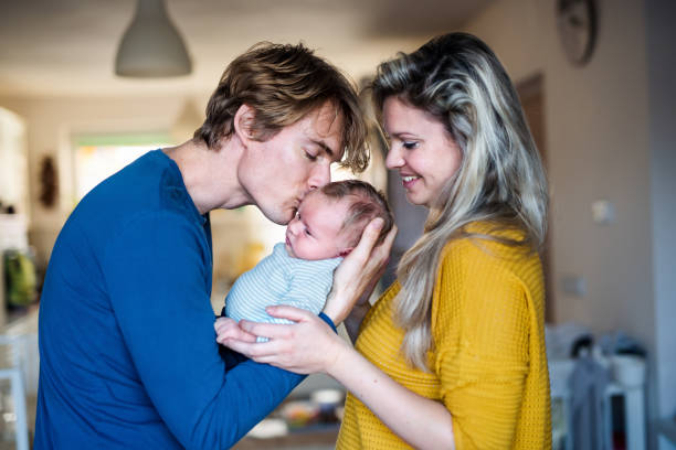 beautiful young parents with a newborn baby at home, kissing. - mother baby new kissing imagens e fotografias de stock