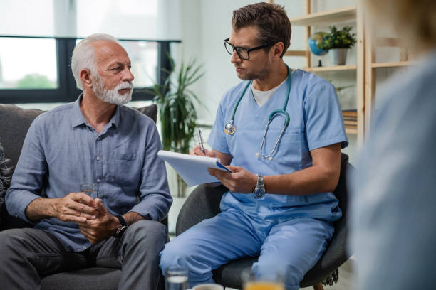 general practitioner taking notes and communicating with senior patient while being in home visit. - healthcare and medicine nurse doctor general practitioner imagens e fotografias de stock