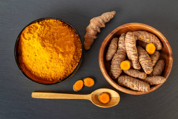 istock Turmeric roots and powder on gray slate background, overhead shot 1152836564