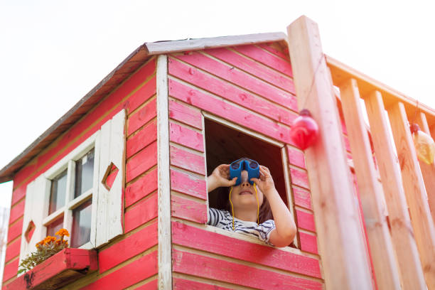 istock Boy in a wooden playhouse looking through a binocular 1152841177