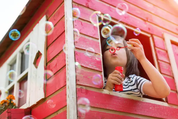 Photo of Boy blowing bubbles in a wooden playhouse