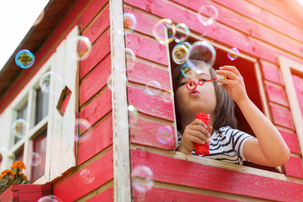 bolhas de sopro do menino em um playhouse de madeira - bubble wand bubble child playful - fotografias e filmes do acervo