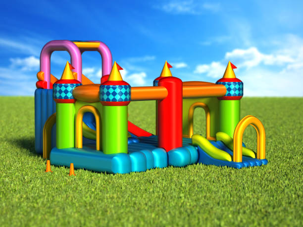 istock Multi-colored bouncy castle standing on grass against blue sky 1152842602