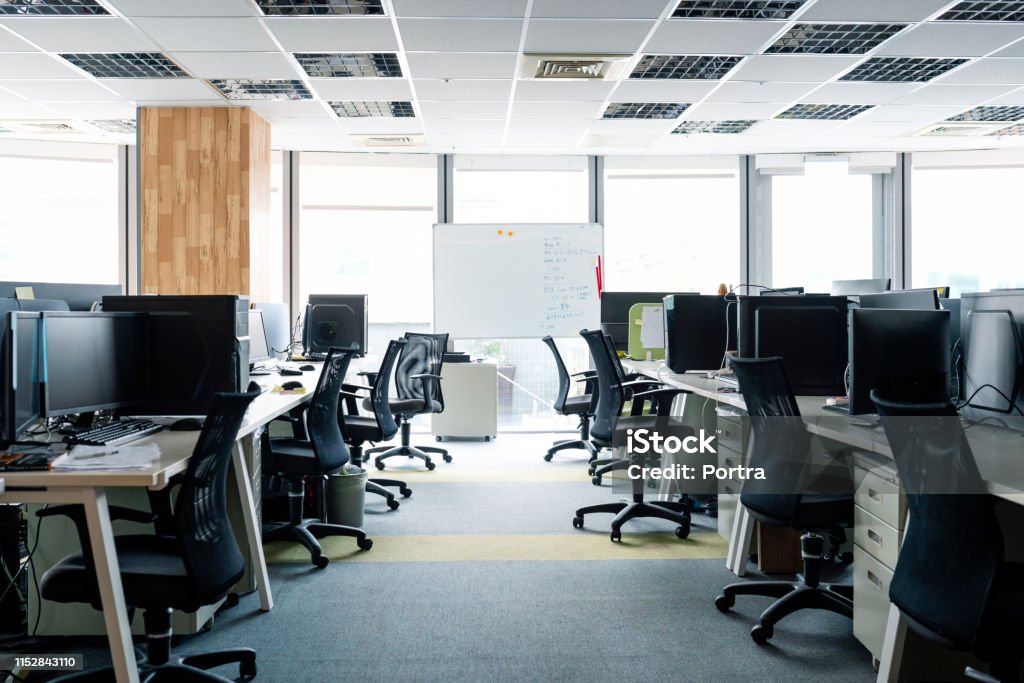 Empty chairs and Desktop PCs at desks in office Empty chairs at desks in office. Desktop PCs are on tables. Interior of modern work place with furniture. Office Stock Photo