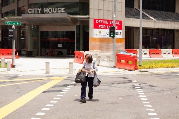 Asian senior woman is crossing street at traffic light stock photo