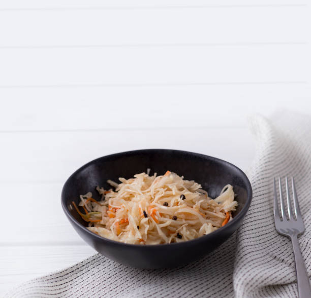istock Fermented cabbage. Traditional russian appetizer sauerkraut with carrot in craft plate on white wooden table. 1152848241