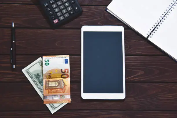 Photo of financial concept, Tablet Pc, calculator, notepad on white background, planning personal income. Hand is typing on the calculator for money plan.