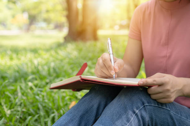 istock poem, poetry and knowledge education concept,  close up sitting writing on notebook in park 1152853824