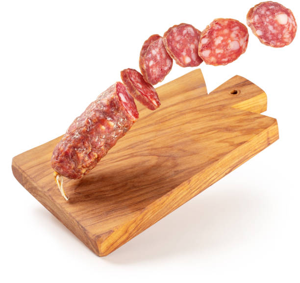 flying salami and chopping board on white background sliced salami flying on a wooden cutting board isolated sliced salami stock pictures, royalty-free photos & images