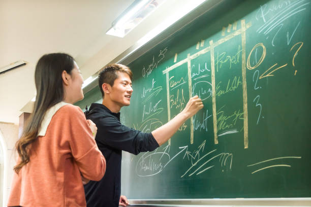 istock College student using the blackboard explaining to his friend 1152854791