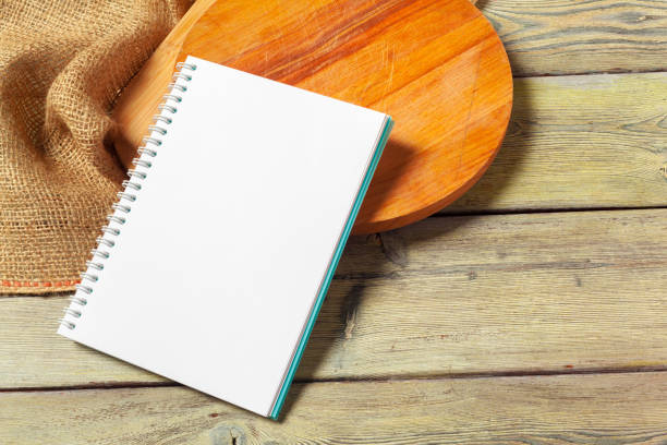 istock Blank sheet of opened notepad and kitchen utensils on  table with tablecloth, copy space 1152857341