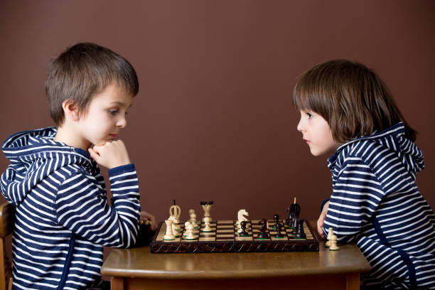 istock Little boy, playing chess. Smart kid, isolated, playing chess against his brother 1152861296