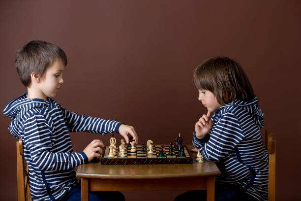 istock Little boy, playing chess. Smart kid, isolated, playing chess against his brother 1152861320