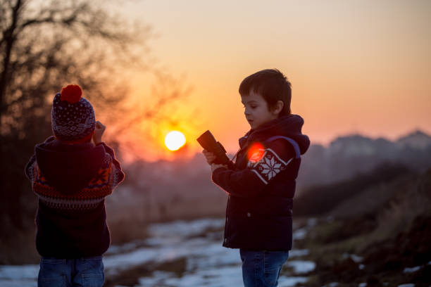 duas crianças pequenas, meninos, explorando a natureza com binóculos - searching landscape sunset winter - fotografias e filmes do acervo