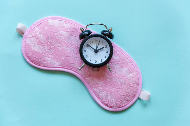 istock Sleeping mask and alarm clock on blue background 1152867253
