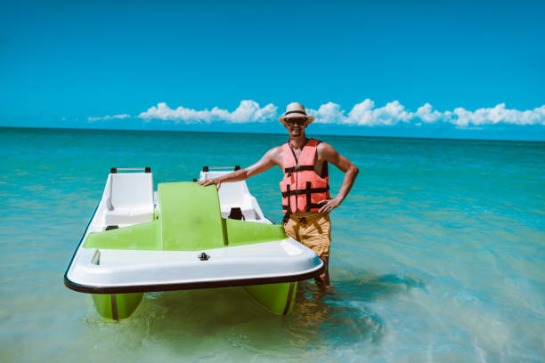 Happy Male Presenting His Favorite Method Of  Beach Fun Happy Male Presenting His Favorite Method Of  Beach Fun pedal boat stock pictures, royalty-free photos & images