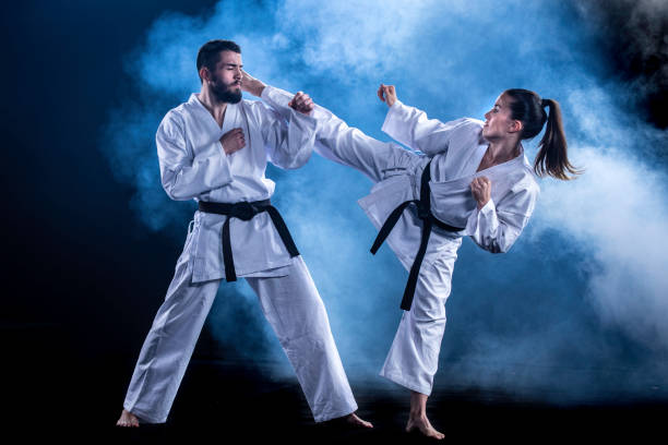 karateka femenina haciendo una patada de vuelta en el compañero de sparring masculino - martial arts women tae kwon do black belt fotografías e imágenes de stock