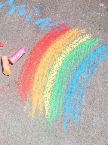 A colorful rainbow made with chalk on the sidewalk.